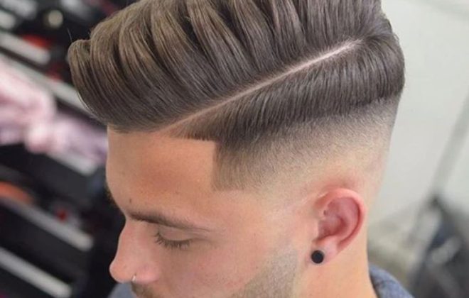 A man is posing with his comb over fade haircut