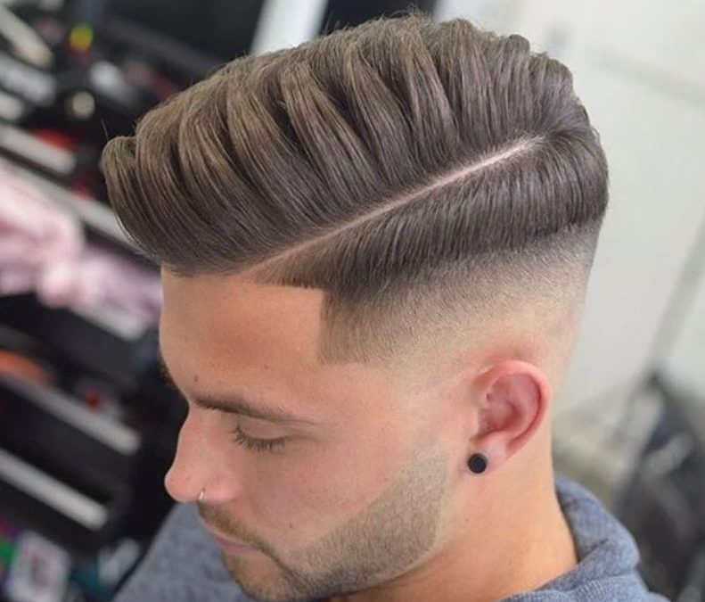 A man is posing with his comb over fade haircut