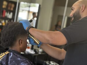 GI Bill approved cosmetology schools, FAFSA cosmetology programs near me, financial aid for cosmetology school, military benefits cosmetology training, affordable cosmetology school with GI Bill, Barber using clippers on a young client.