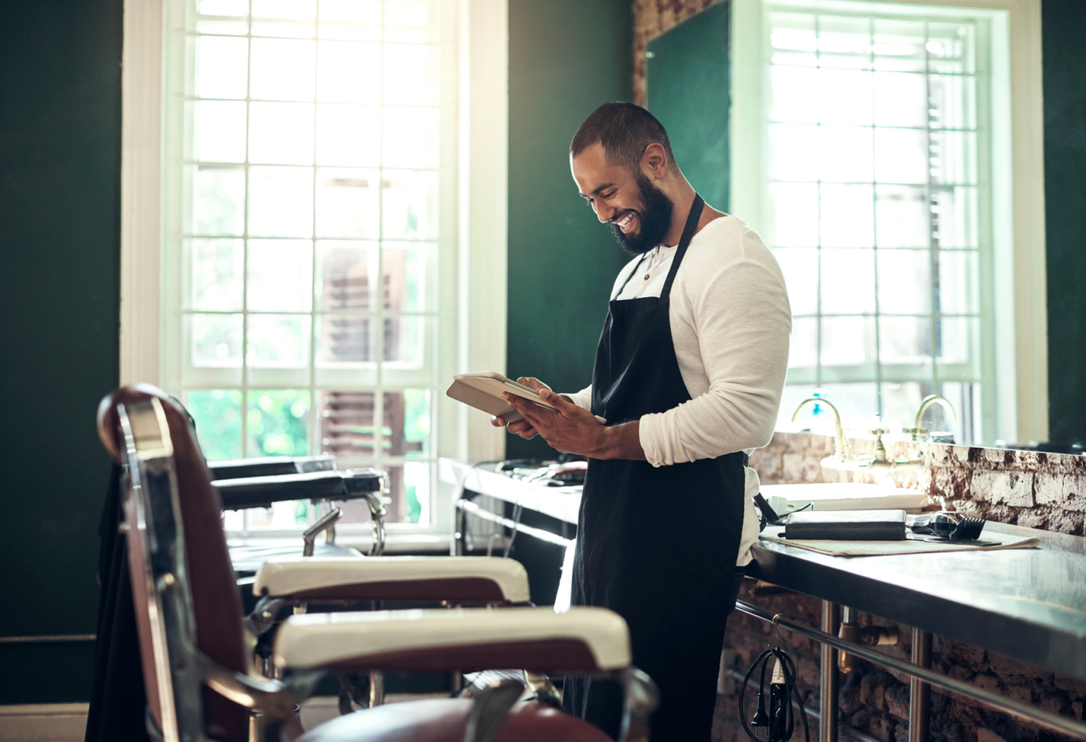 Man in apron reading at barbershop