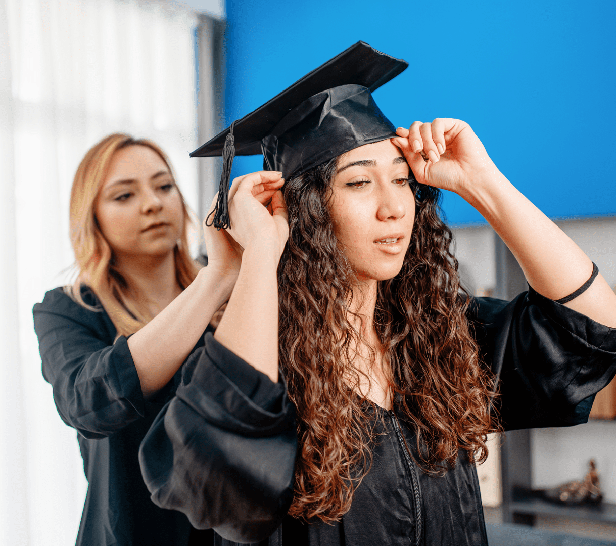 Friends helping each other with graduation attire