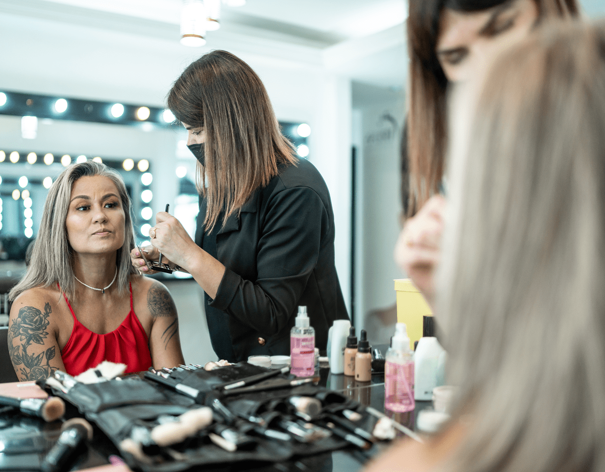 Woman getting makeup applied by stylist
